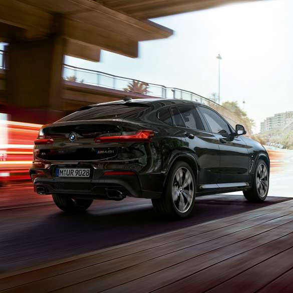 BMW X4 M40i, vue de trois quarts avant. Extérieur de la BMW X4 M40i en Saphierschwarz metallic, en mouvement, vue de trois quarts avant avec bandes lumineuses.