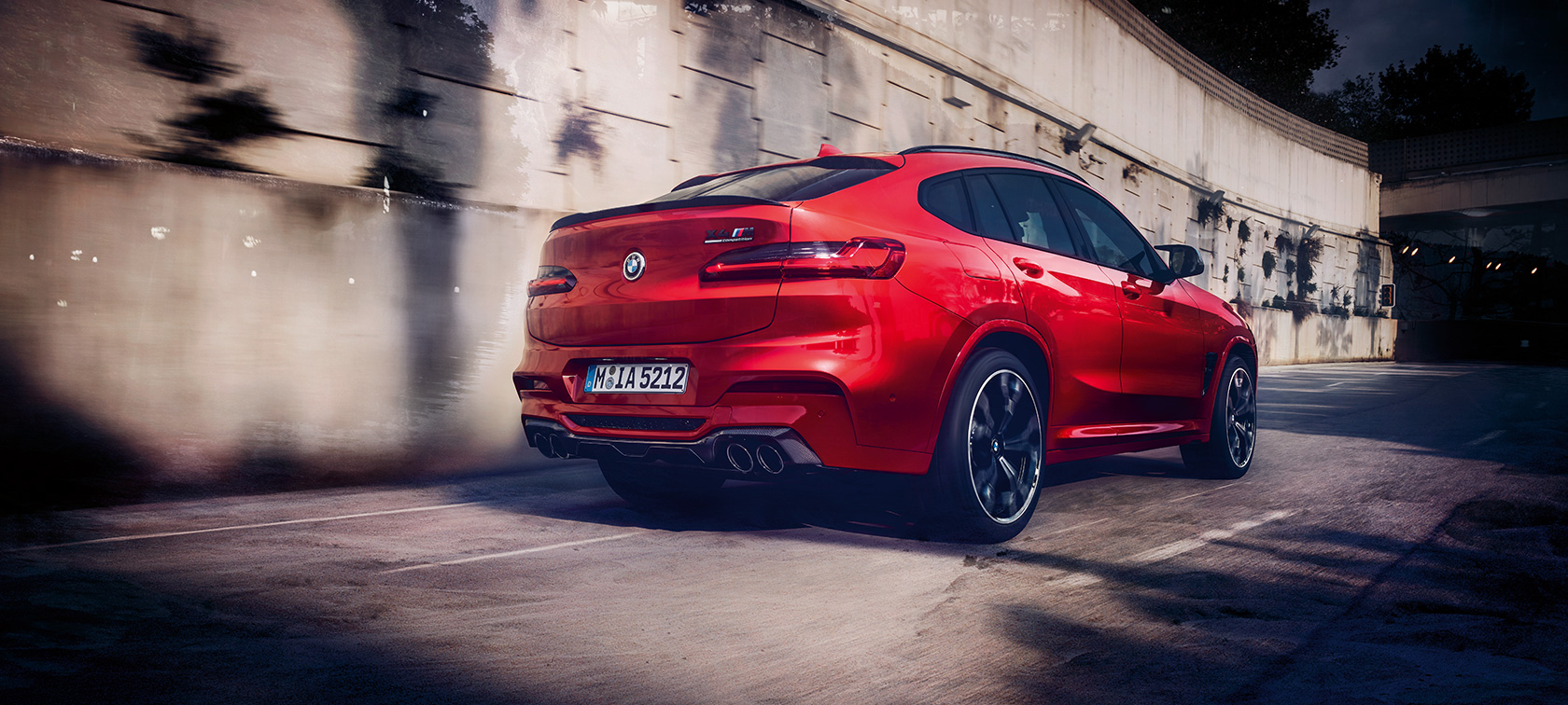 Extérieur de la BMW X4 M Competition, vue de trois quarts arrière. Extérieur de la BMW X4 M Competition en Toronto Rot metallic, en mouvement, vue de trois quarts arrière.