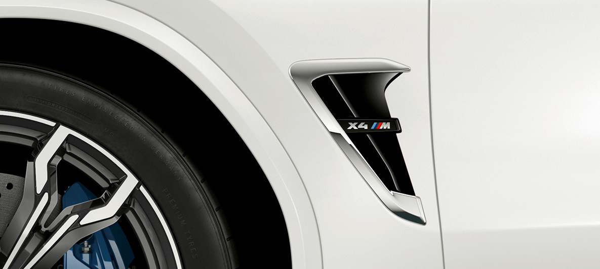 BMW X4 M, naseaux M. Extérieur de la BMW X4 M en Alpinweiß, avant, naseaux M avec accents chromés et insigne du modèle.