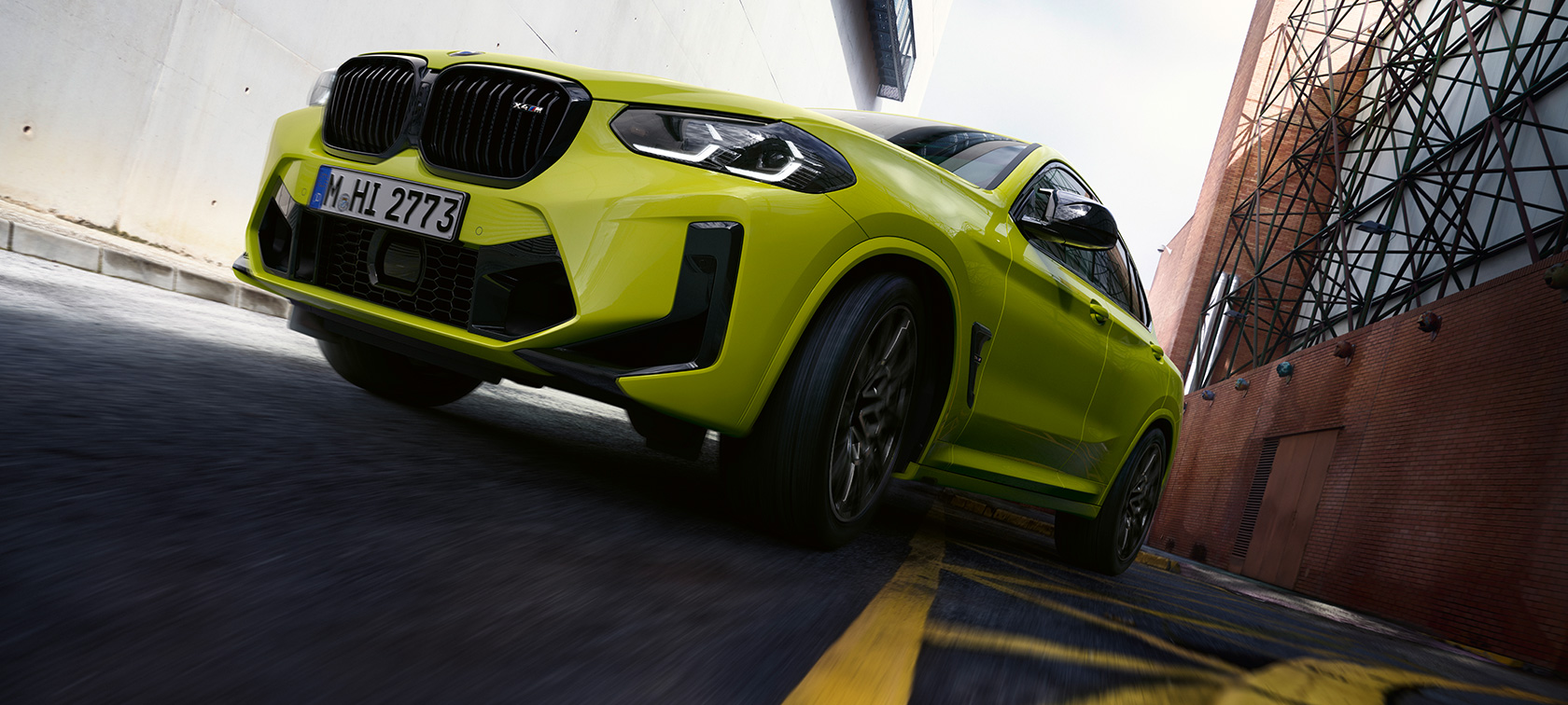 Vue de trois quarts face avec contre-plongée BMW X4 M Competition F98 LCI 2021 BMW X4 M Competition F98 LCI Facelift 2021 Sao Paulo Gelb vue de trois quarts face avec contre-plongée en mouvement dans un canyon urbain