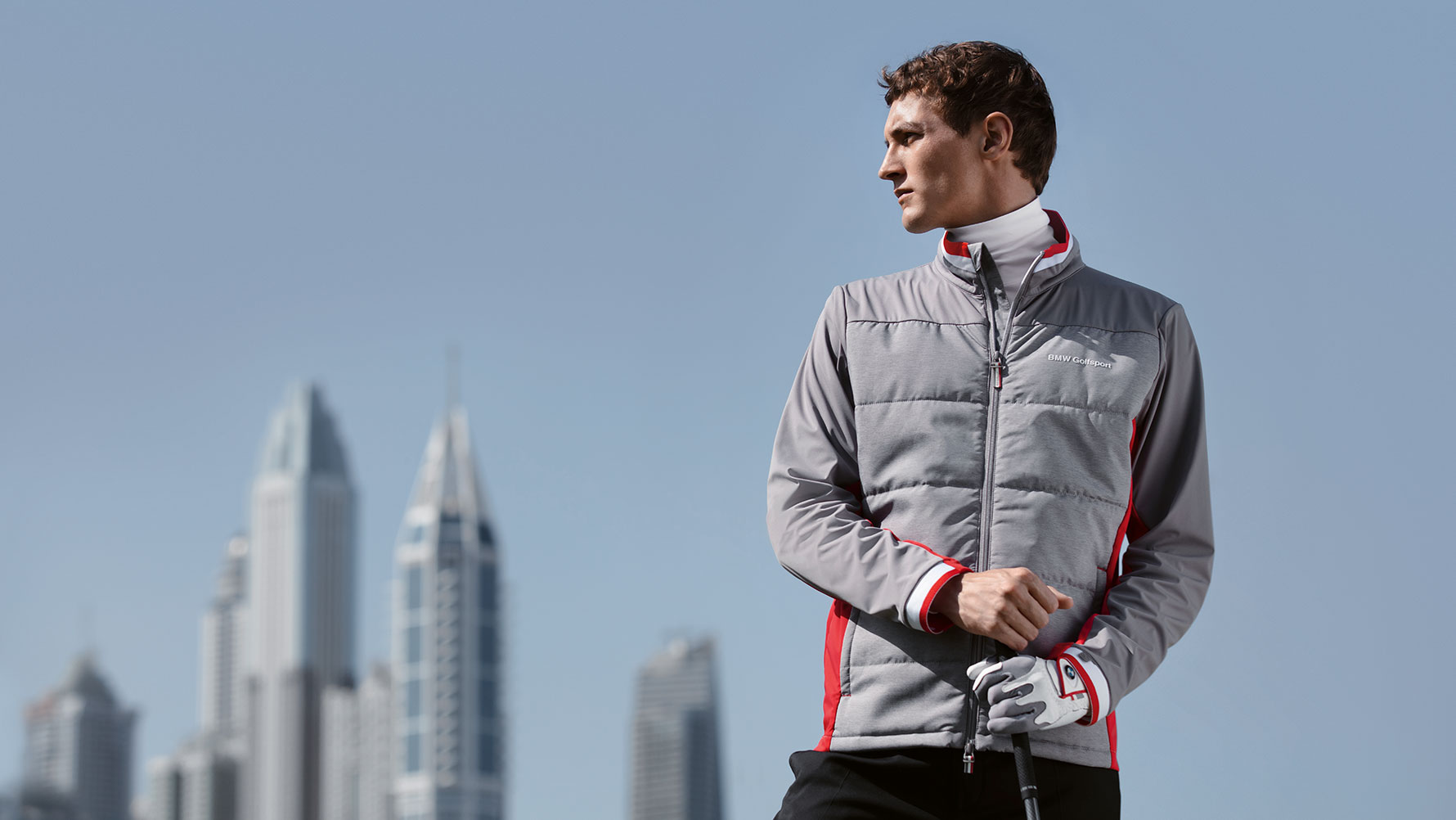 Sur la photo, l’homme présente des articles de la Collection BMW Golfsport appuyé contre un décor de grande ville. Sur la photo, l’homme présente des articles de la Collection BMW Golfsport appuyé contre un décor de grande ville.