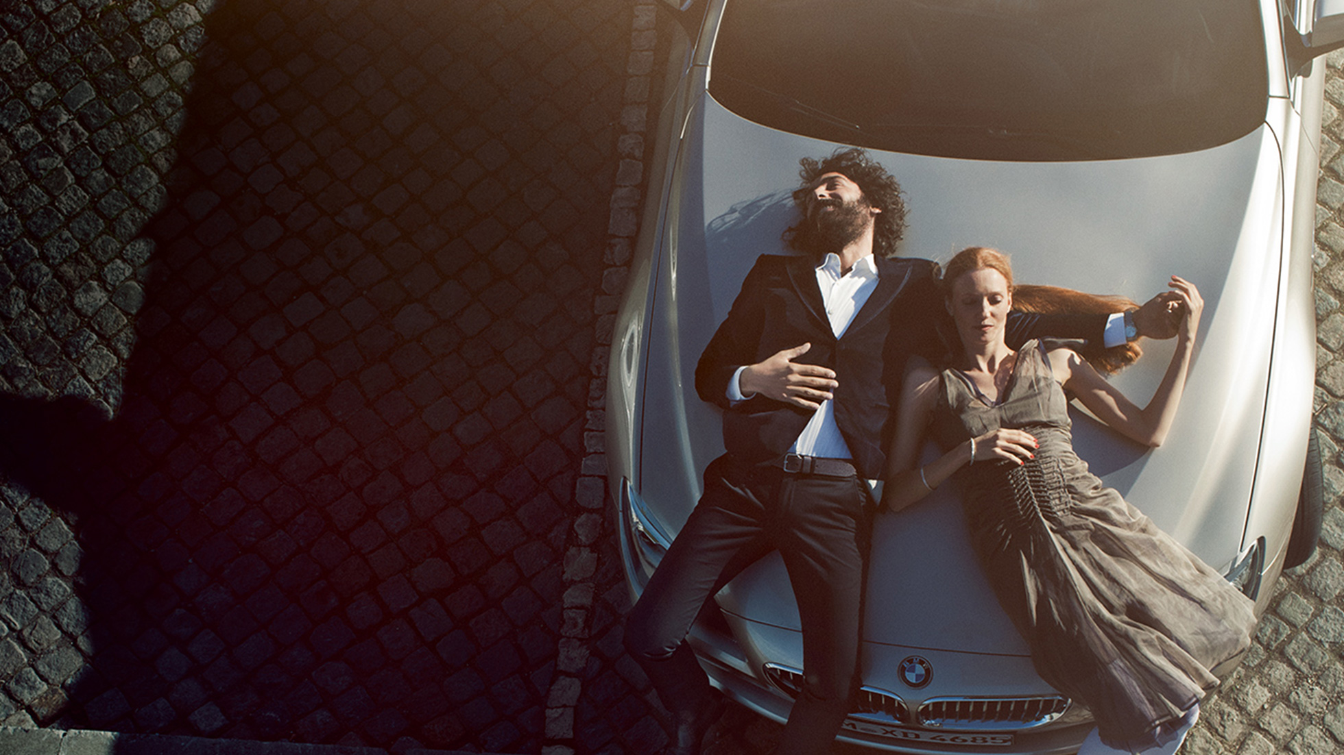 BMW Service huile moteur d'origine BMW BMW Service huiles moteur d’origine Homme et femme couchés en toute décontraction sur le capot moteur d'une BMW