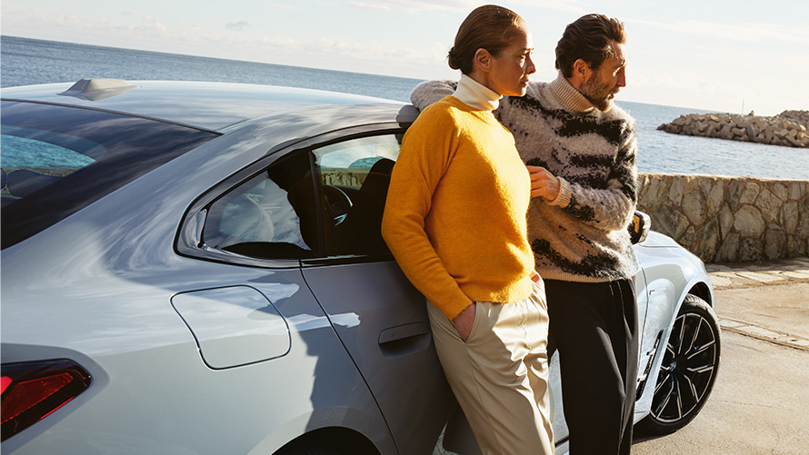 BMW Serenity durées et échéances pour voitures neuves BMW Serenity, homme et femme assis sur une BMW i4 au large de la côte