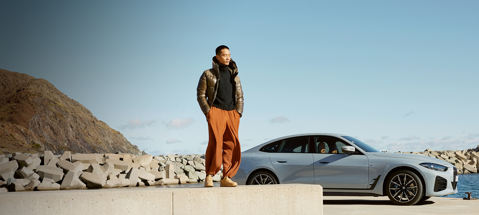 BMW Serenity BMW Serenity, homme devant une BMW i4 sur la côte